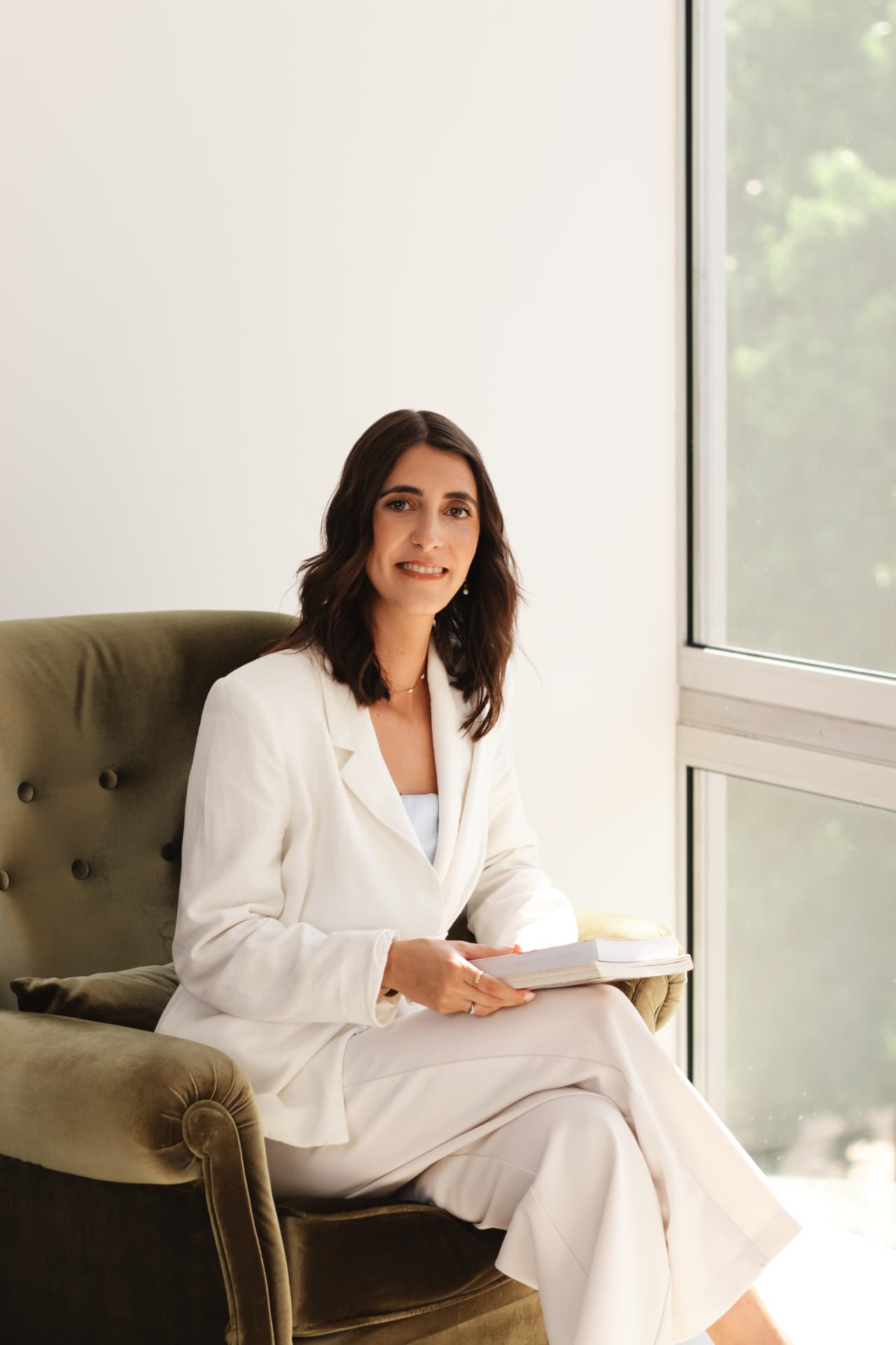 Catarina Amaro sentada num cadeirão verde com um caderno